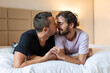 © Graphicroyalty - Happy gay couple lying down on the bed at home, hugging and flirting. LGBT gay couple love moments happiness concept