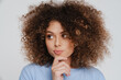 Young beautiful attractive curly woman with puckered lips touching chin