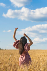 Girl in a field of yellow wheat against the sky with clouds