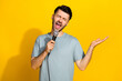 Photo of positive talented man dressed stylish clothes hand hold microphone singing favorite song isolated on yellow color background
