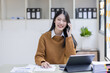 © David - Young employee Asian Business woman calling on phone and working with account documents achieves an graph business in workplace finance business concept