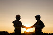 Engineer and worker handshake at construction site silhouette