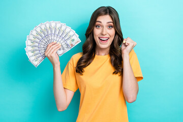 Sticker - Photo of young adorable pretty cute funny woman hold cash dollars fist up toothy smile reaction winner lottery success rich isolated on aquamarine color background