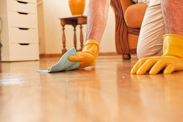 Wall Mural - Handsome man cleaning floor in his house with a piece of cloth and using gloves, working hard