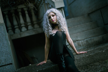 Wall Mural - Portrait of a gothic girl, looking like a doll lolita, posing next to an old stone staircase of a castle or an old abandoned tower