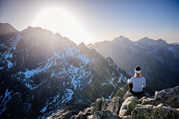beautiful blonde woman enjoys reaching the summit in the slovak tatras and looks at the gerlach moun