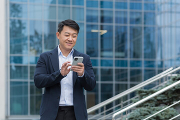 young handsome male asian businessman is waiting for a business meeting. he is standing near the off