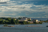 Fototapeta Na sufit - Helsinki, Finland - July 20, 2022: Suomenlinna Fortress from the sea. Ramparts and yellow buildings and terrain of the Naval Academy o Pikku Musta island under blue cloudscape. Islets in sea