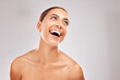 Woman, laughing and skincare face glow on gray studio background for body care, self love wellness or dermatology success. Smile, happy or beauty model with facial makeup cosmetics and wow expression