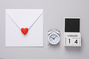 February 14 wooden calendar with alarm clock and calendar with heart on gray background. Valentine's Day