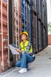 © asean studio - Photo of a young beautiful professional western female brunette engineer inspecting containers in a shipping containers yard to ensure the content and delivery information is correct