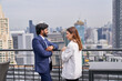 © bank215 - Businessman and businesswoman are talking a business deal on rooftop and cityscape view