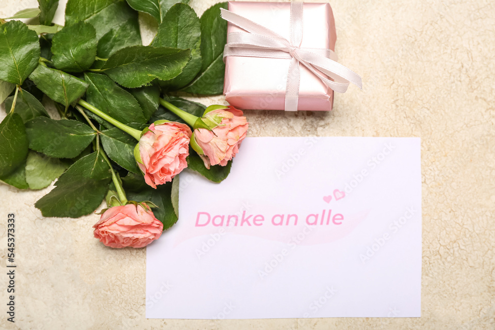 Card with text DANK AN ALLE, roses and gift box on grunge background
