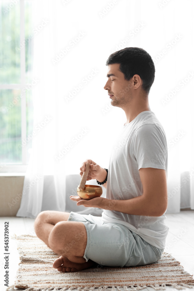Young man with Tibetan singing bowl at home