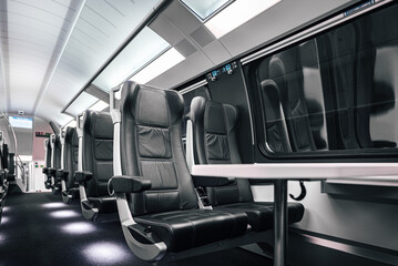 Table and empty leather seats by window in modern passenger intercity train