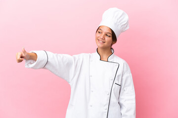 Wall Mural - Little caucasian chef girl isolated on pink background giving a thumbs up gesture