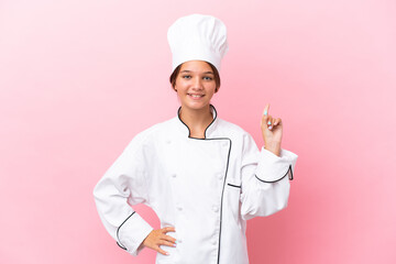 Wall Mural - Little caucasian chef girl isolated on pink background showing and lifting a finger in sign of the best