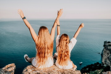 Sea family vacation together, happy mom and teenage daughter hugging and smiling together over sunset sea view. Beautiful woman with long hair relaxing with her child. Concept of happy friendly family