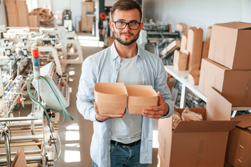 Wall Mural - Holding beautiful wooden packages. Print house worker in white clothes is indoors