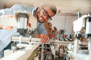 Wall Mural - Using the cutting machine. Print house worker in white clothes is indoors