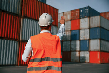 Rear view. Controlling the process. Male worker is on the location with containers