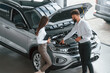 © standret - Hood is opened. Man with woman in white clothes are in the car dealership together