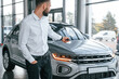 © standret - Closing the automobile by remote keys. Young man in white clothes is in the car dealership
