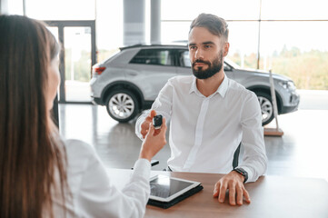 Wall Mural - Automobile keys for the new owner. Man with woman in white clothes are in the car dealership together