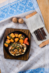 Sticker - Pork with fried mushrooms, potatoes, zucchini and onions in a cast iron pan, rustic style.