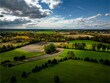 Aerial shot of a green field surrounded by trees during the on a sunny day in Auburn New York