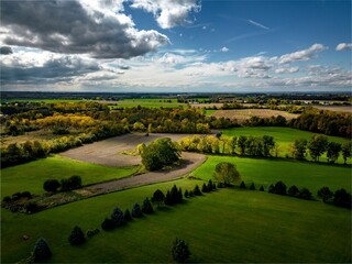 Wall Mural - Aerial shot of a green field surrounded by trees during the on a sunny day in Auburn New York
