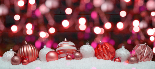 Wall Mural - Festive christmas ornaments advent celebration holiday holidays banner greeting card - Pink, red and white christmas baubles, balls on snow, black wooden wall and bokeh lights in background