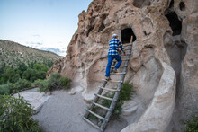 A Visitor, Man, Climbing A Wooden Ladder, Right To Inspect A Cavate In A Soft Volcanic Rock Cliff, A Historic Home Of Ancestral Pueblo Indians, , Talus House, Bandelier NM
