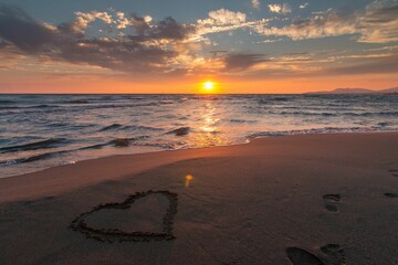 Wall Mural - Scenic shot of a heart on an empty sandy beach at sunset