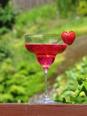 Sticker - Vertical shot of a glass with a pink fruity cocktail and a strawberry on the glass