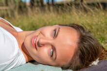 Face Of Young Blue-eyed Woman Lying On The Grass