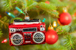 A Christmas ornament in the shape of a radio or boom box hanging on the Christmas tree.