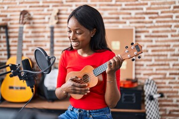 Young african american woman musician playing ukelele at music studio