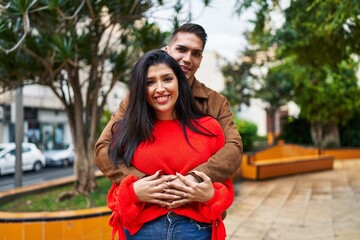 Wall Mural - Man and woman couple smiling confident hugging each other at park