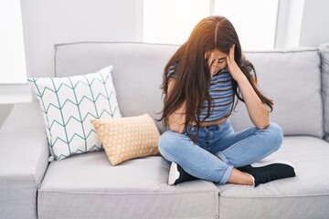 Sticker - Young hispanic girl stressed sitting on sofa at home