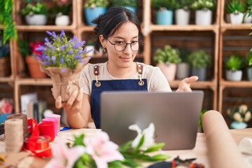 Canvas Print - Young hispanic woman working at florist shop doing video call smiling friendly offering handshake as greeting and welcoming. successful business.