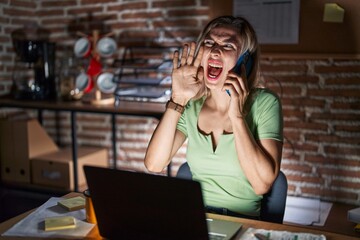 Sticker - Young beautiful woman working at the office at night speaking on the phone shouting and screaming loud to side with hand on mouth. communication concept.