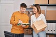 © Krakenimages.com - Young man and woman ecommerce business workers writing on book holding package at office