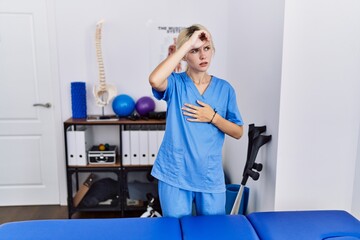 Canvas Print - Young physiotherapist woman working at pain recovery clinic touching forehead for illness and fever, flu and cold, virus sick