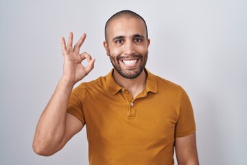 Canvas Print - Hispanic man with beard standing over white background smiling positive doing ok sign with hand and fingers. successful expression.