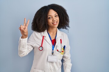 Wall Mural - Young african american woman wearing doctor uniform and stethoscope smiling looking to the camera showing fingers doing victory sign. number two.