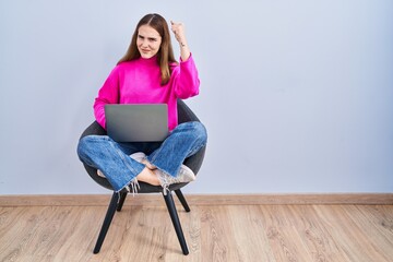 Canvas Print - Young hispanic girl working using computer laptop angry and mad raising fist frustrated and furious while shouting with anger. rage and aggressive concept.