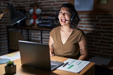 Poster - Young hispanic woman working at the office at night angry and mad screaming frustrated and furious, shouting with anger. rage and aggressive concept.