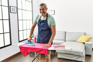 Sticker - Middle age grey-haired man smiling confident ironing clothes at home