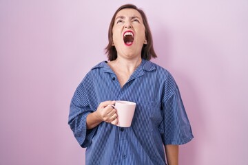 Poster - middle age hispanic woman drinking a cup coffee angry and mad screaming frustrated and furious, shou